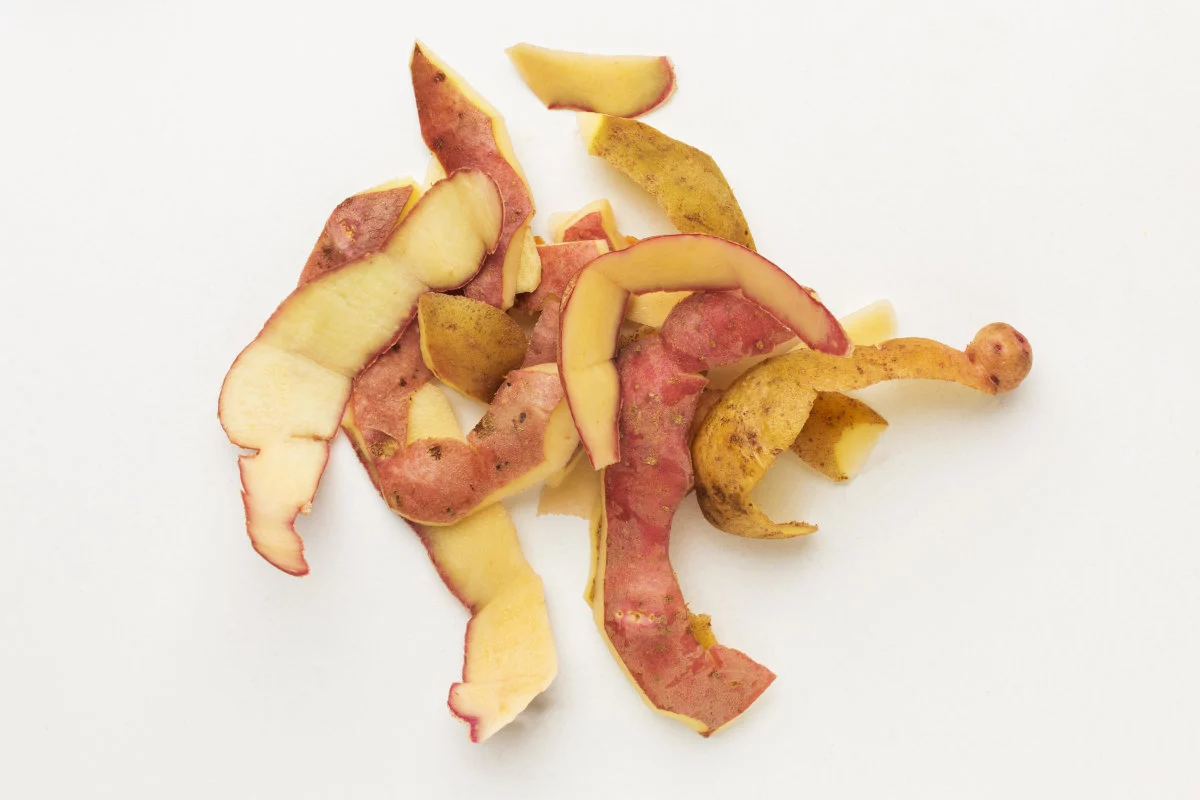 Varie bucce di patate rosse e gialle sono sparse su una superficie bianca.